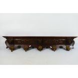 An oak and brass wall mountable coat rack decorated with three carved lion masks and foliate