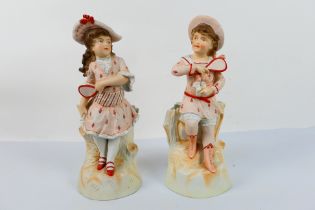 A pair of bisque figures depicting a boy and girl playing tennis, approximately 37 cm (h).