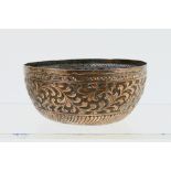 An Indonesian white metal bowl with foliate scroll repousse decoration to the body and crossed Kris