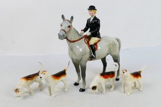 A Beswick huntswoman figure on grey horse, 21 cm (h) and four fox hounds.
