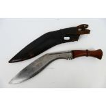 A vintage kukri with 30 cm (l) blade, wooden hilt and brass chapri, housed in leather scabbard.