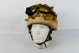 A British military combat helmet, Mk6, with camouflage cover and goggles.