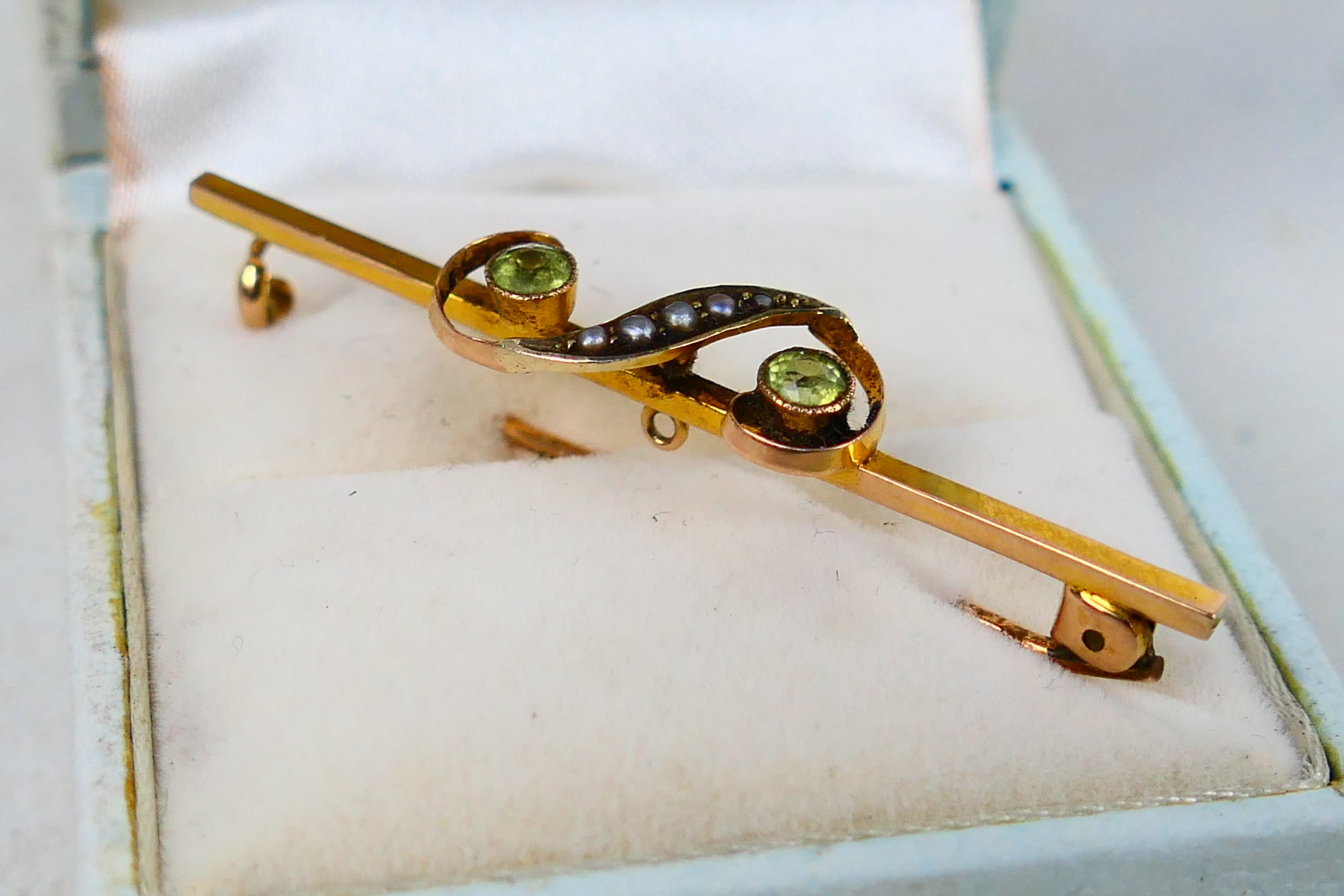 A 9ct gold bar brooch set with peridot and seed pearl in the form of a gruppetto or turn, 5 cm (l), - Image 3 of 3