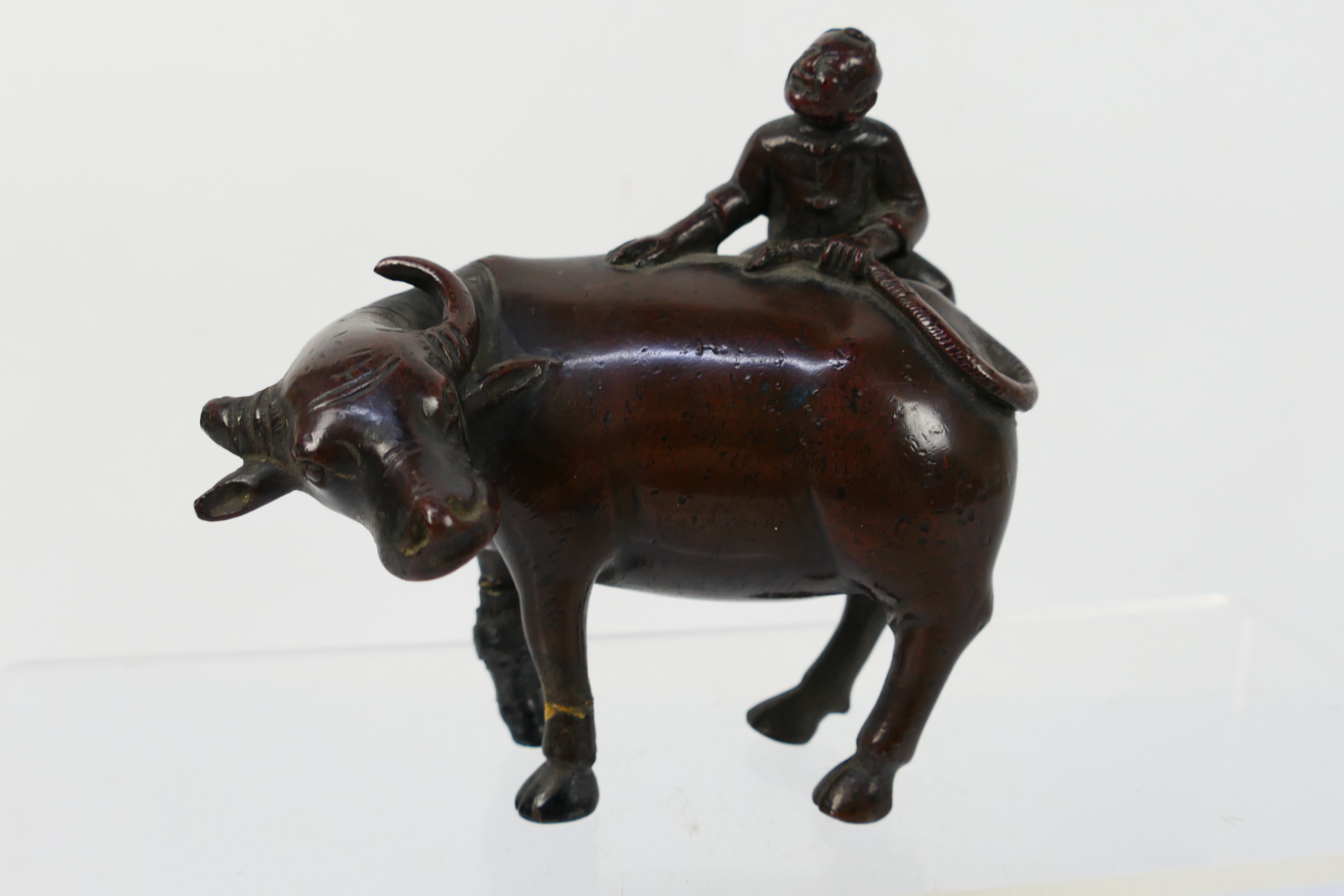 A Chinese bronze Buffalo and Boy group modelled as a boy atop a buffalo (A/F),