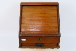 A vintage slope front desk organiser, tambour opening enclosing a fitted interior,