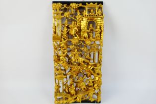 A Chinese carved gilt wood panel depicting numerous warriors engaged in battle,