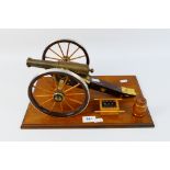 A cast brass and wood table cannon mounted to plinth with model barrel and cannonballs,