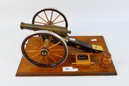 A cast brass and wood table cannon mounted to plinth with model barrel and cannonballs,