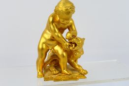 A small gilt metal group depicting a putto wrestling a lion, approximately 12 cm (h),