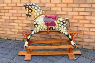 A carved wood dappled rocking horse on trestle base, base length 114 cm,