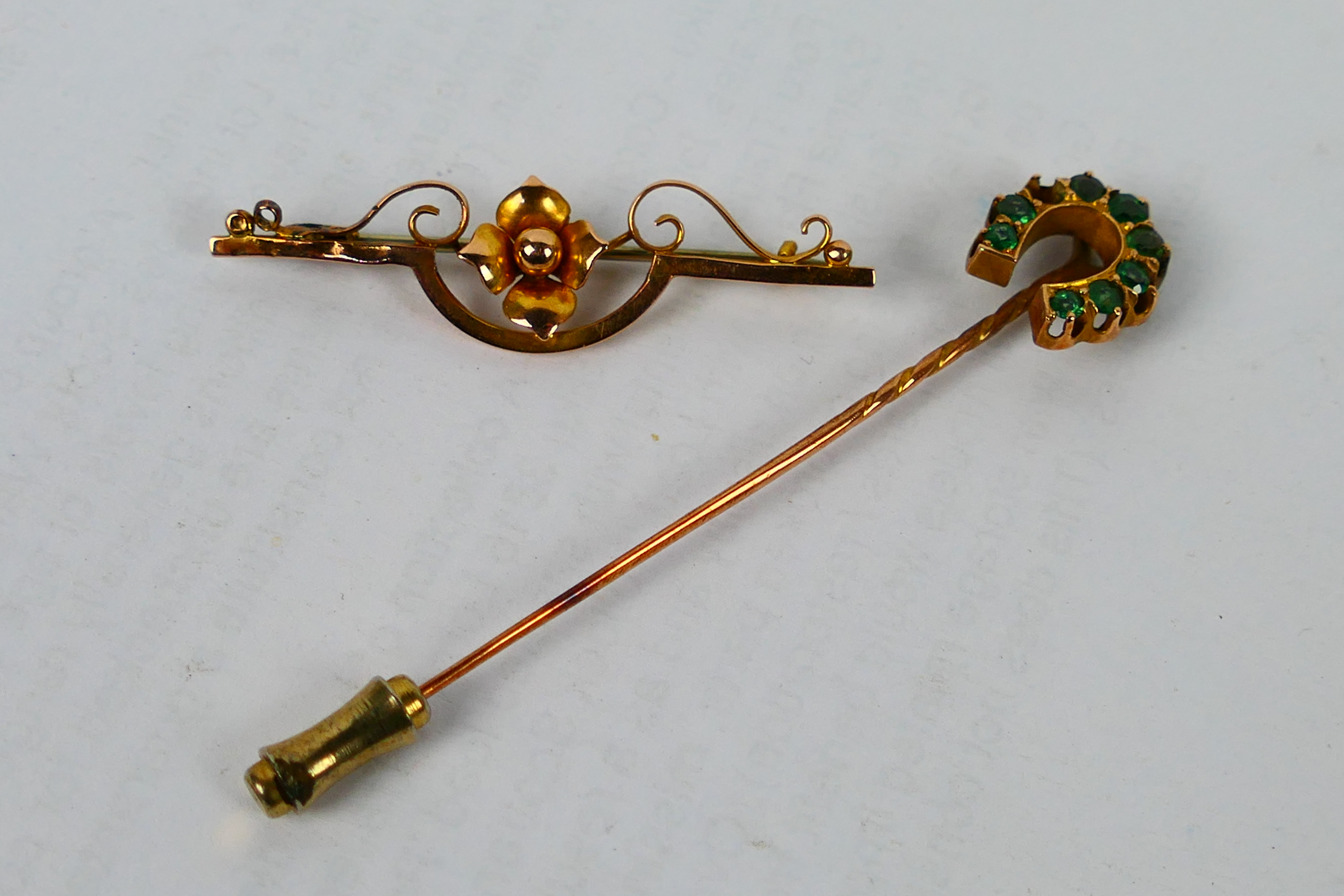 A yellow metal bar brooch with central floral motif,