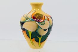Moorcroft - A small Moorcroft Pottery Trial vase with floral decoration reserved against a peach