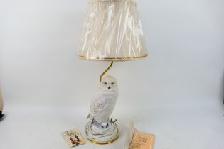 A decorative Franklin Mint table lamp with snowy owl form base designed by Raymond Watson,