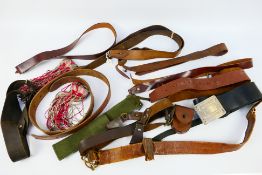 A collection of military and similar belts, predominantly leather.