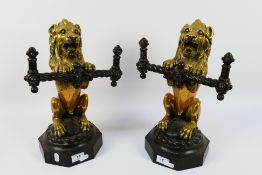 A pair of Victorian cast iron and gilt brass fire dogs, in the form of lions sejant erect,