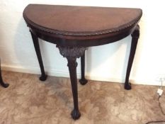 An early 20th century demi-lune hall table, the supports terminating in ball and claw feet,