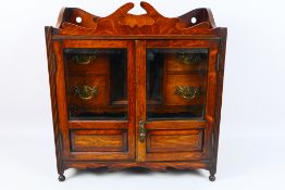 An early 20th century smokers cabinet with twin glazed doors,