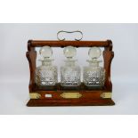 A three decanter oak tantalus with plated mounts, no maker's mark visible.