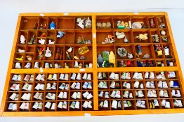 A wooden display housing a quantity of thimbles and small decorative ornaments, 53 cm x 83 cm.