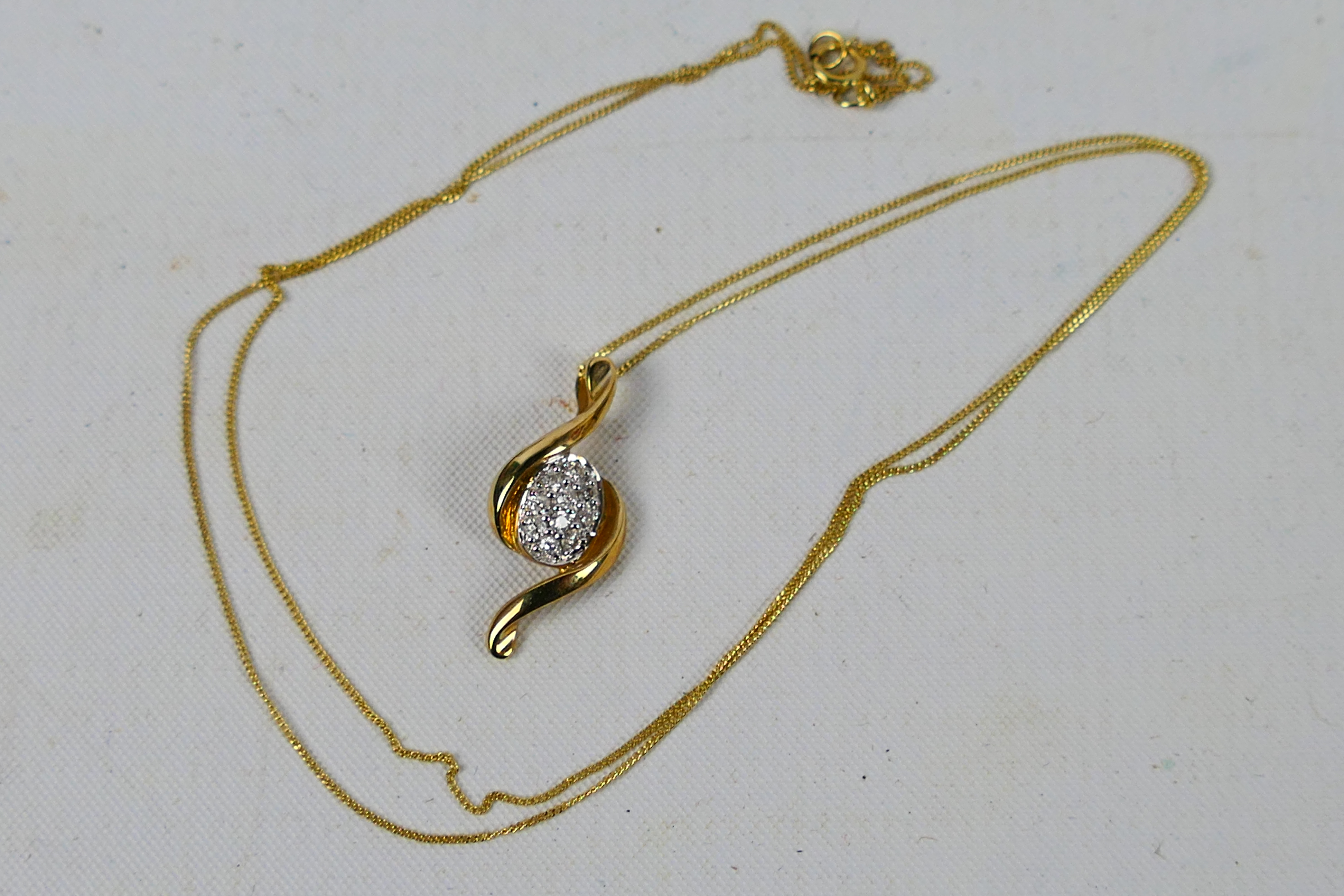 A yellow metal (stamped 375) diamond set pendant on yellow metal fine trace chain stamped 375,