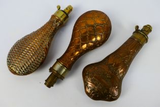 Three copper and brass powder flasks with embossed decoration, one in the Art Nouveau taste.