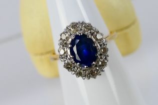 A yellow metal (assessed as 18ct), sapphire and diamond cluster ring,