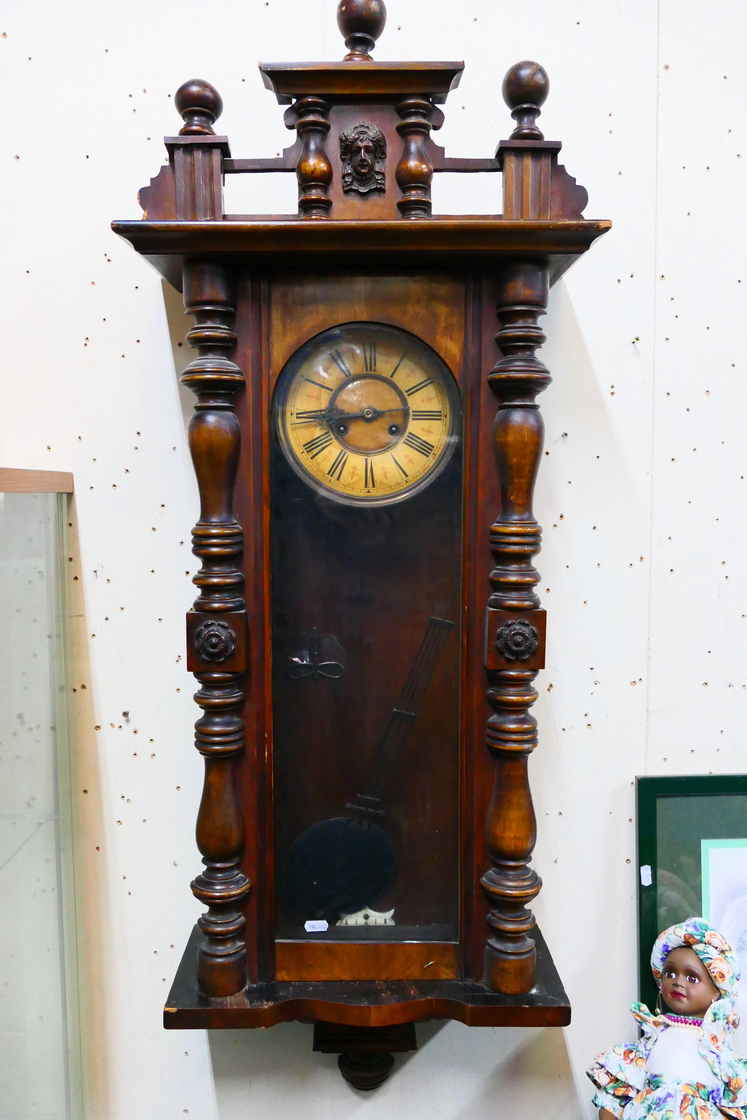 A Vienna-style wall clock. 124 cm (h) x 43 cm (w) x 20 cm (d), with key and pendulum.