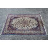 A signed Persian ivory ground rug with central floral medallion,