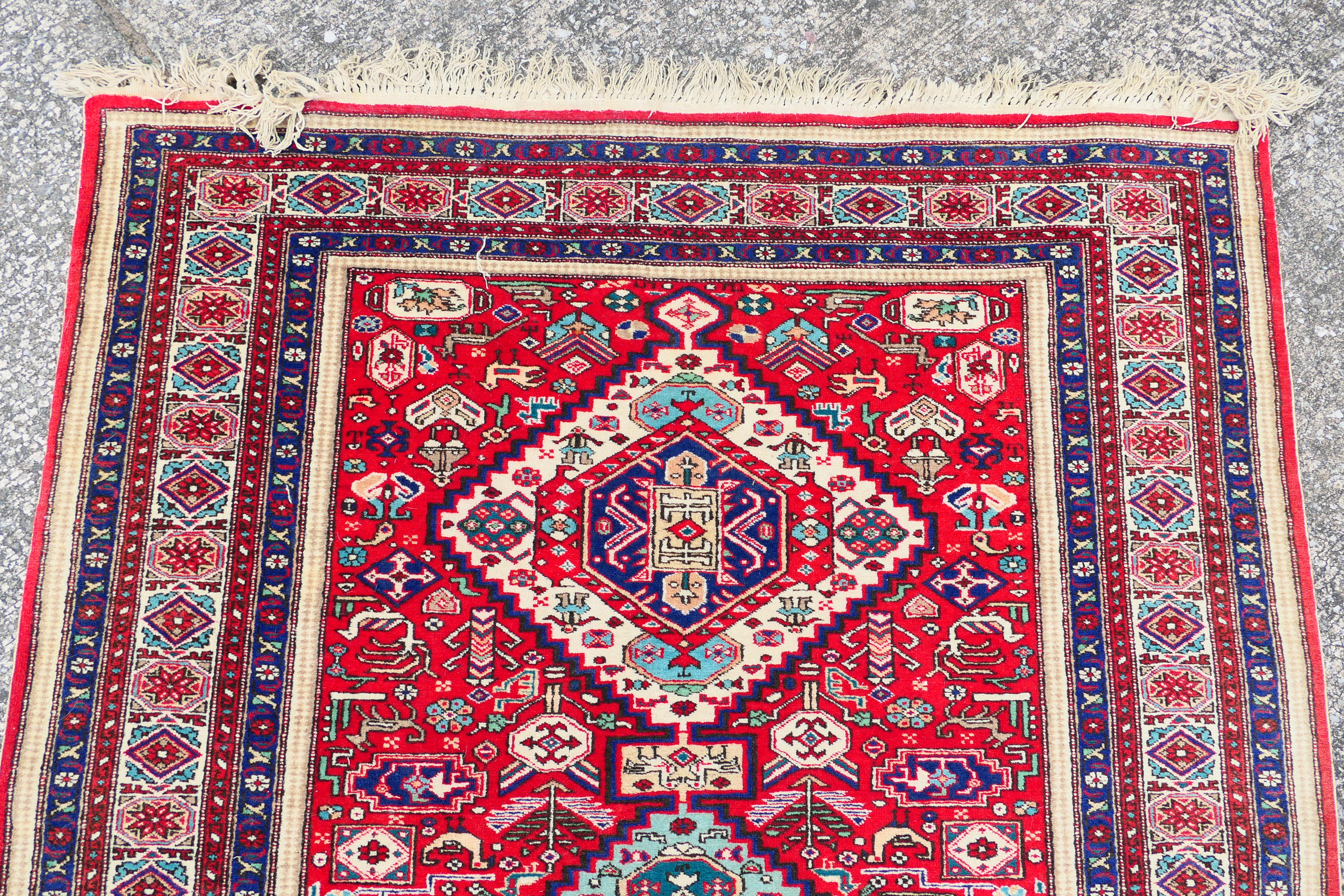 A Persian rug with triple lozenge medallions on a red ground within repeating border, - Image 4 of 5