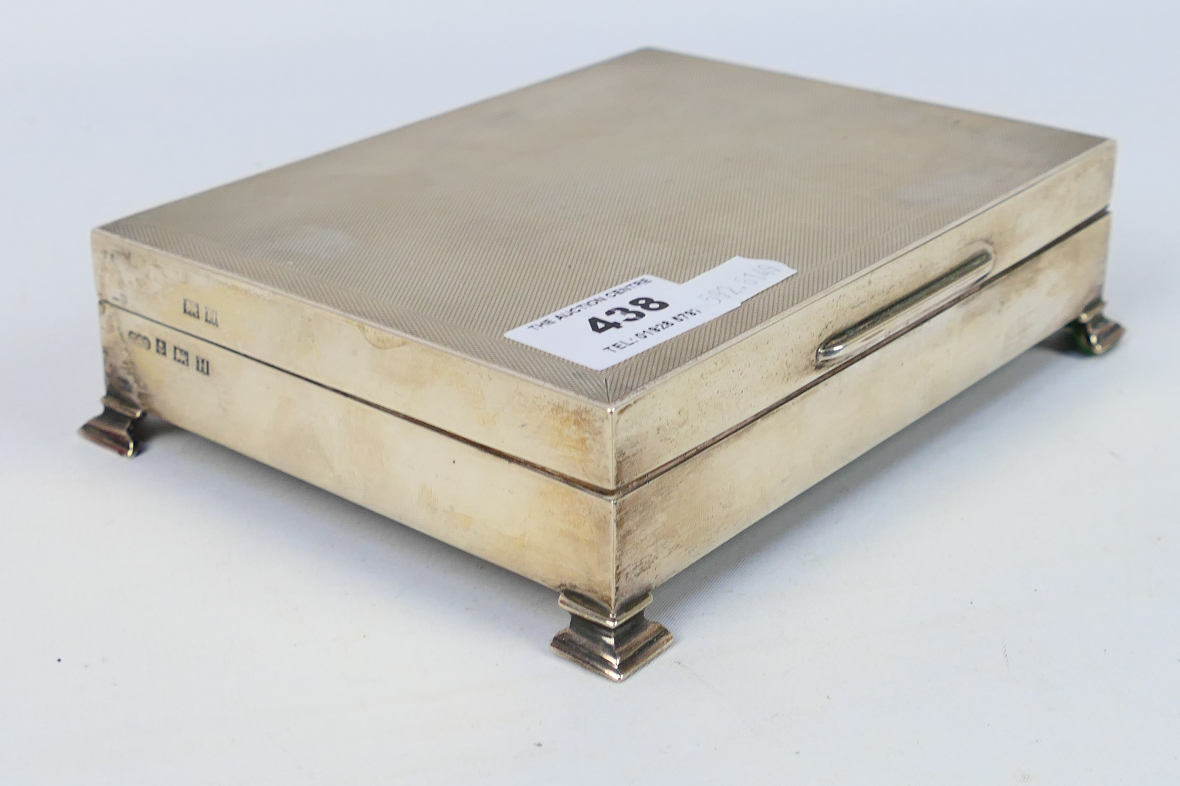 A silver cigarette box with engine turned decoration, raised on bracket feet, Birmingham assay 1957, - Image 3 of 5