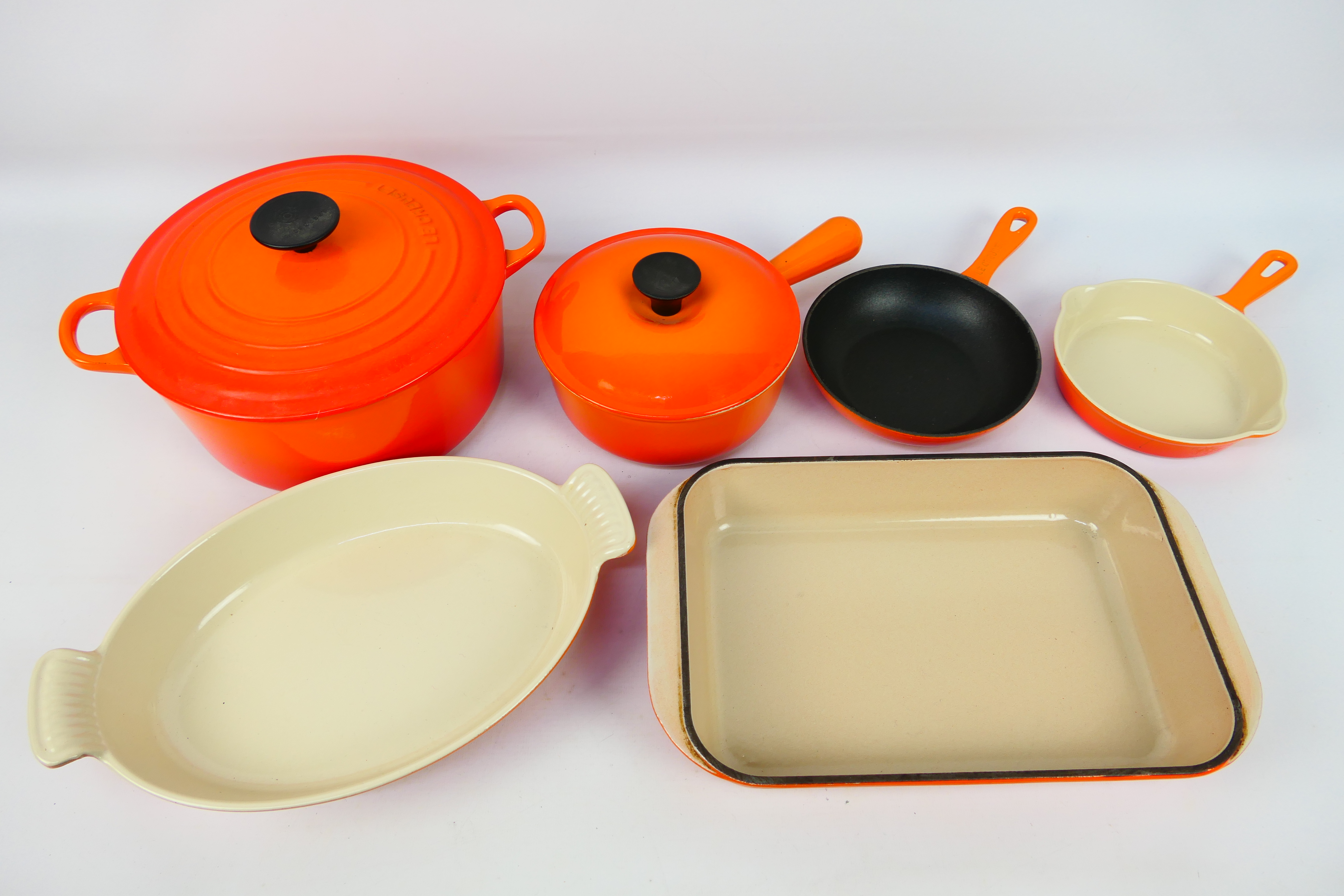 A collection of Volcanic Orange Le Creuset cookwares to include casserole dish and cover (25 cm