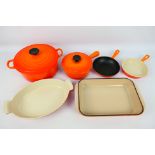 A collection of Volcanic Orange Le Creuset cookwares to include casserole dish and cover (25 cm