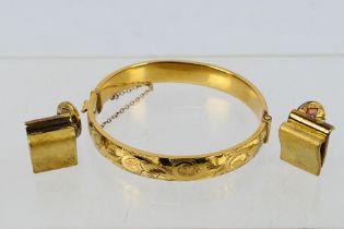 An attractive rolled gold hinged bangle with chased decoration and a vintage pair of Nina Ricci