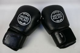 A pair of 16 oz Geezers Palace boxing gloves in black and white.