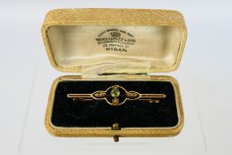 A yellow metal, stamped 15ct, peridot and seed pearl bar brooch, 5 cm (l), approximately 3.4 grams.