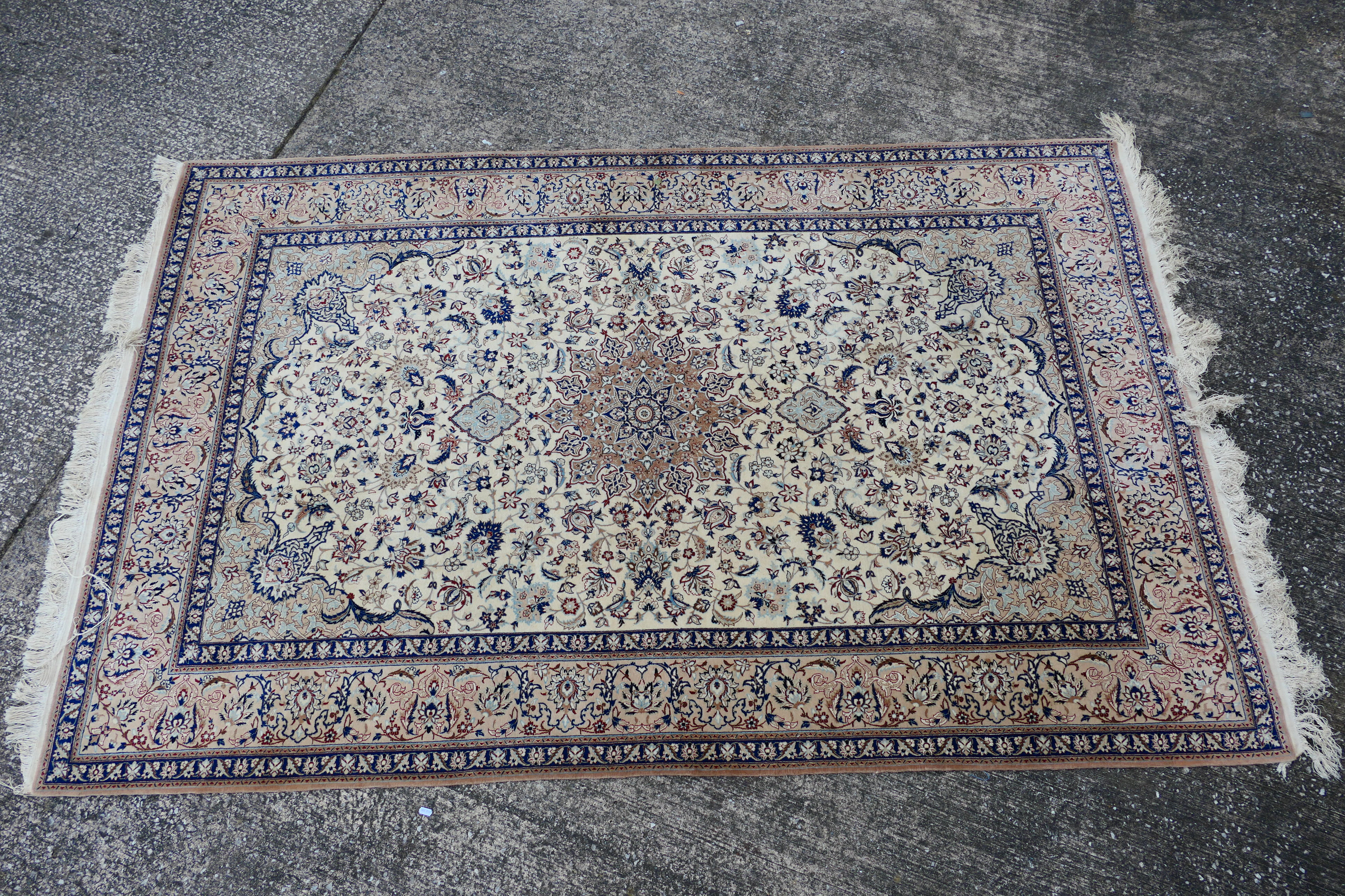 A Persian ivory ground rug with central medallion on a floral field, with foliage scroll border,