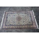 A Persian ivory ground rug with central medallion on a floral field, with foliage scroll border,