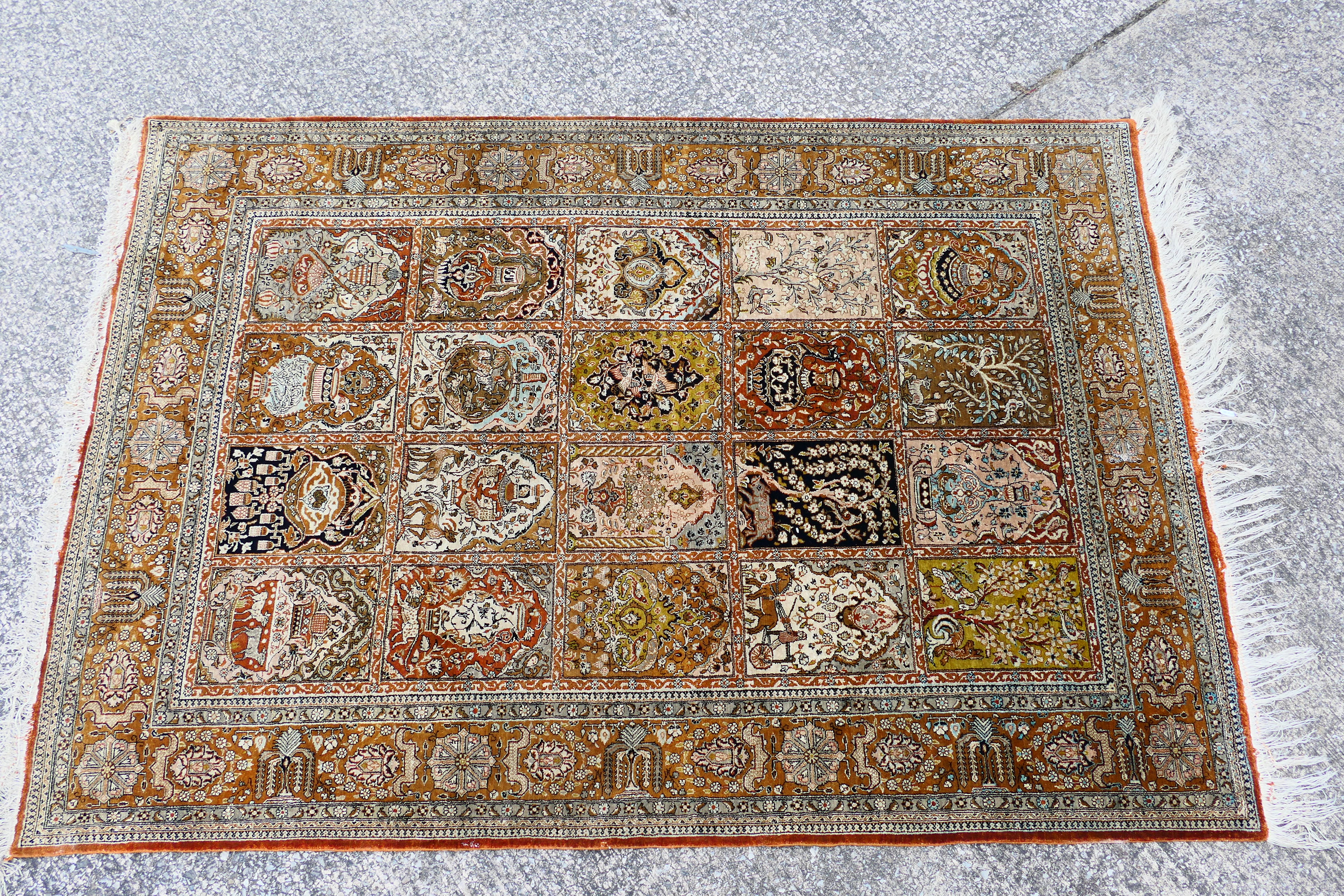 A Persian rug decorated with panels of flowering urns,