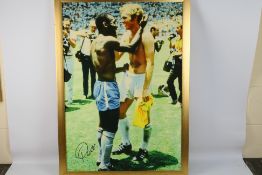 A Reproduction Canvas Print of Pele and Bobby Moore, hand signed by Pele, framed, 88cm by 61cm,