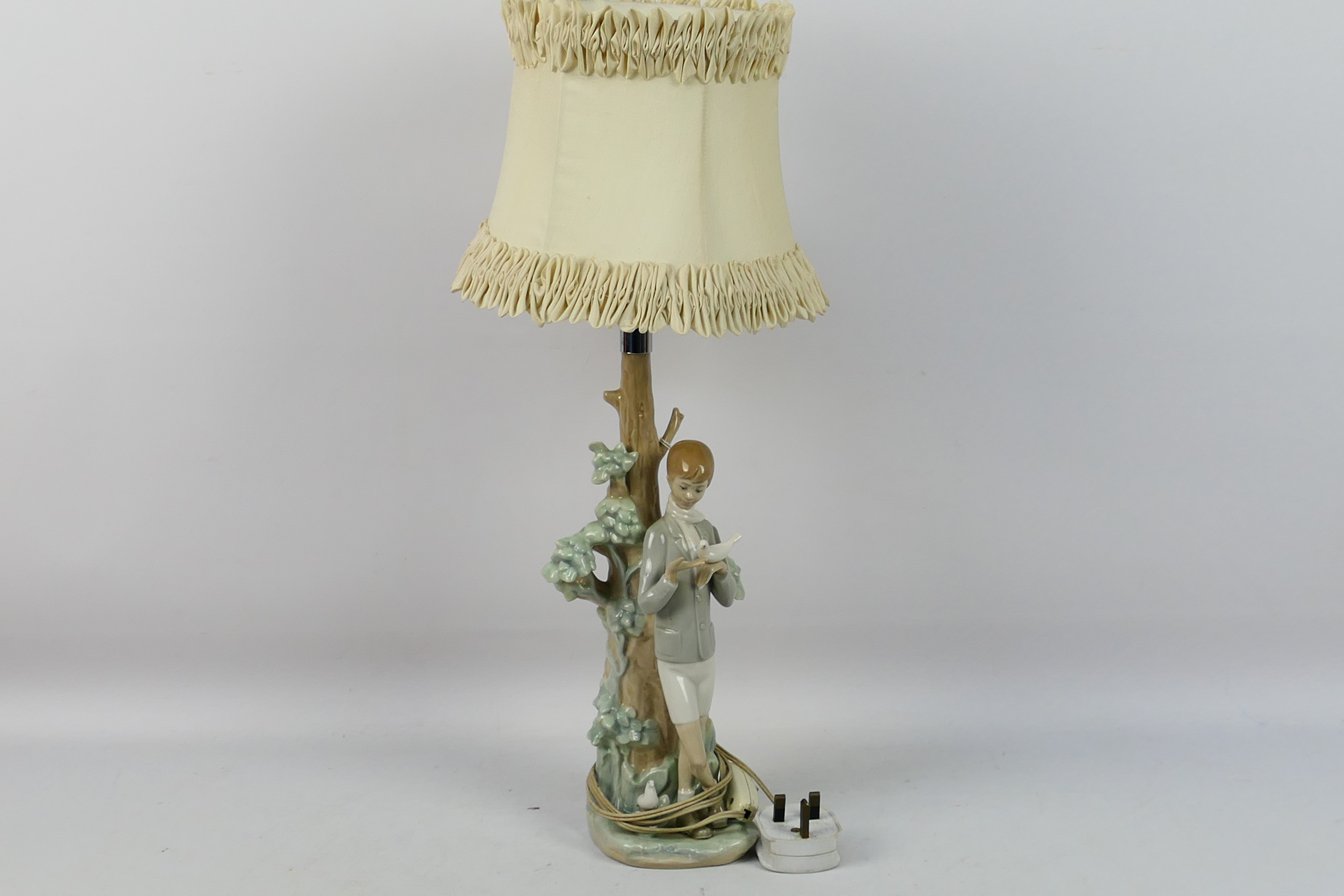 A Lladro figural table lamp depicting a boy feeding a dove, # 4508,