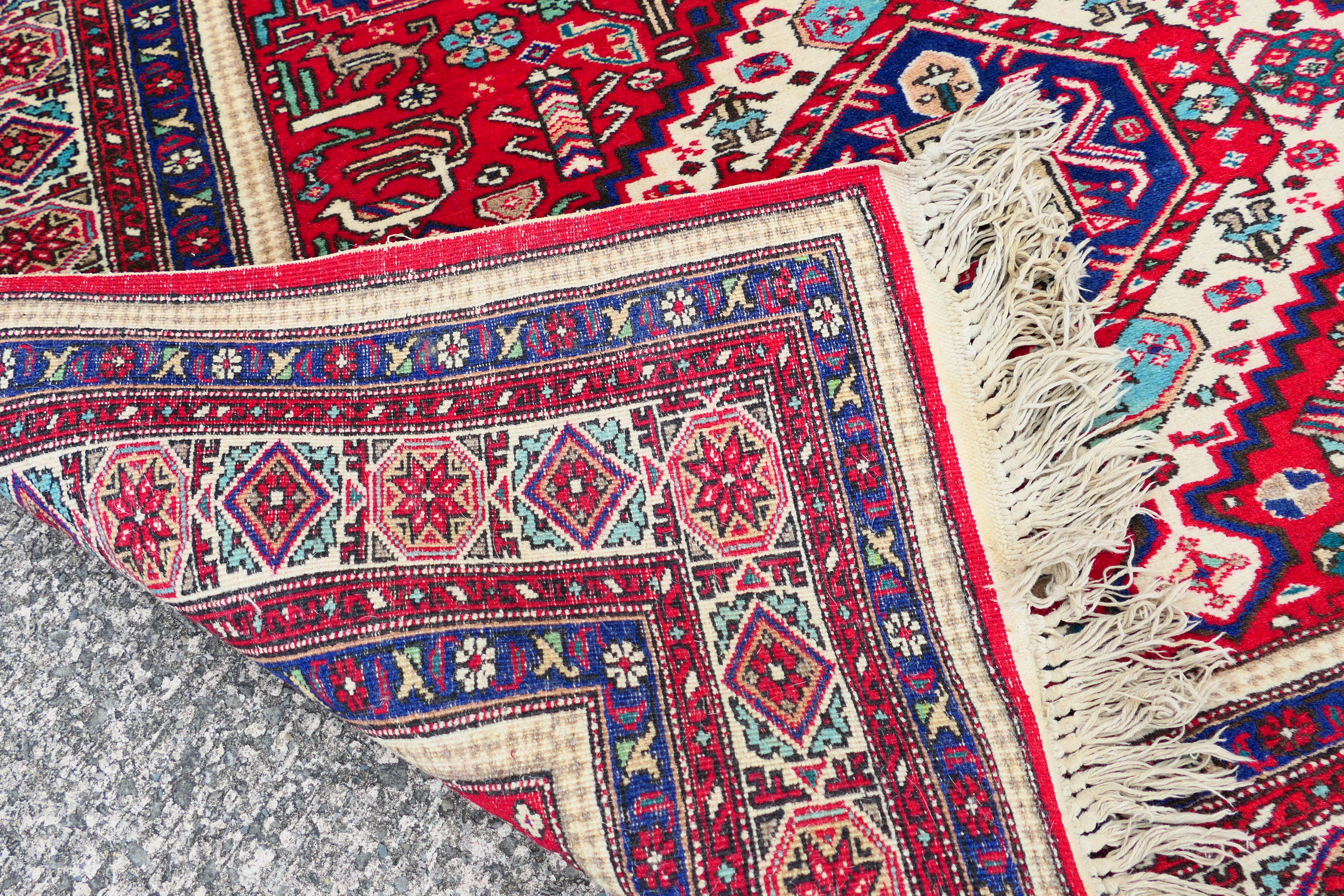 A Persian rug with triple lozenge medallions on a red ground within repeating border, - Image 5 of 5