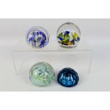 Four decorative paperweights, one with faceted blue glass, Caithness style and similar.