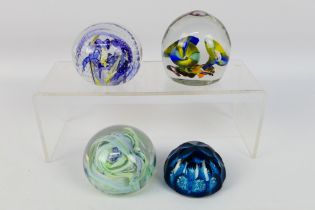Four decorative paperweights, one with faceted blue glass, Caithness style and similar.