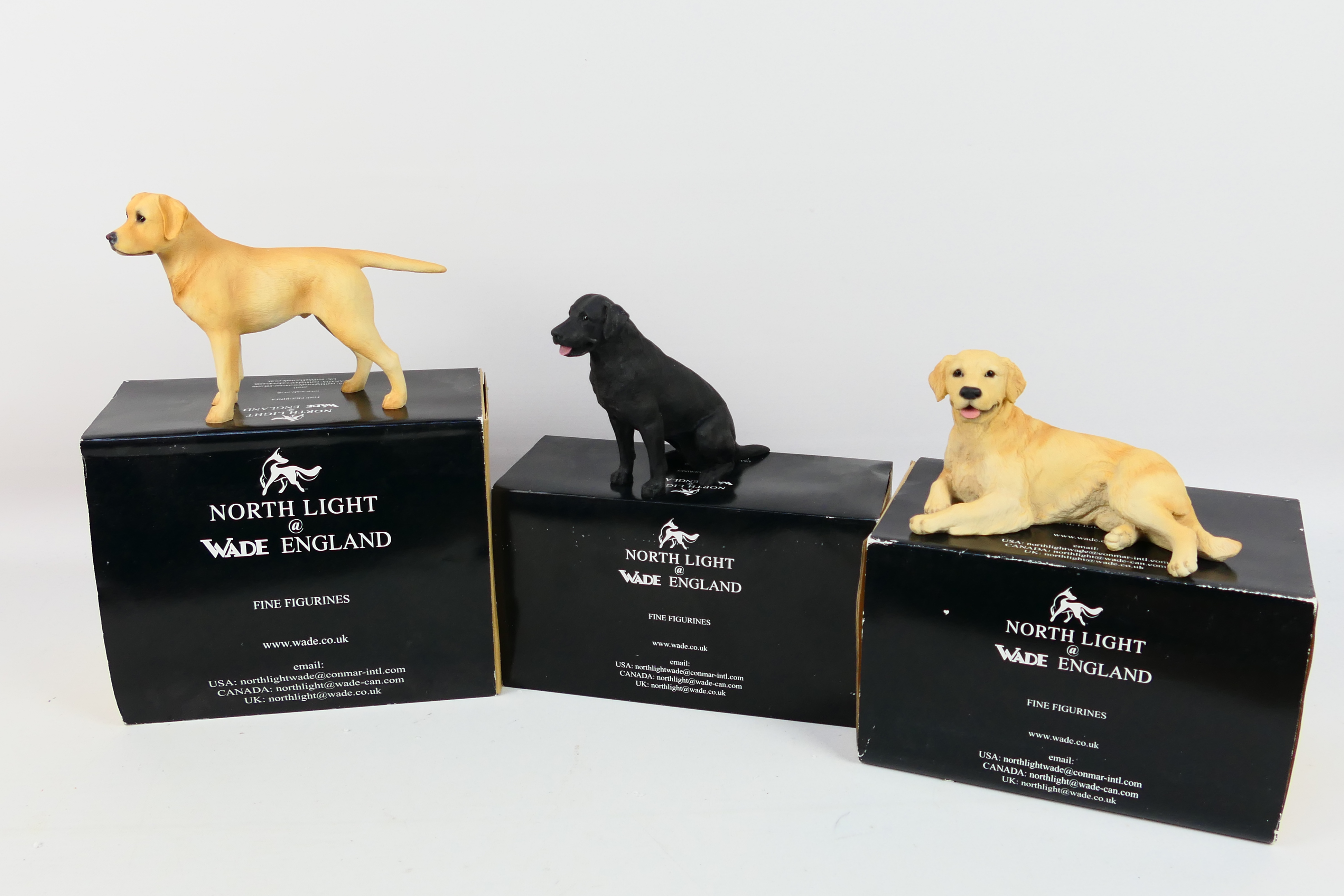 Three boxed dog figures comprising Golden Retreiver, Black Labrador and Yellow Labrador.