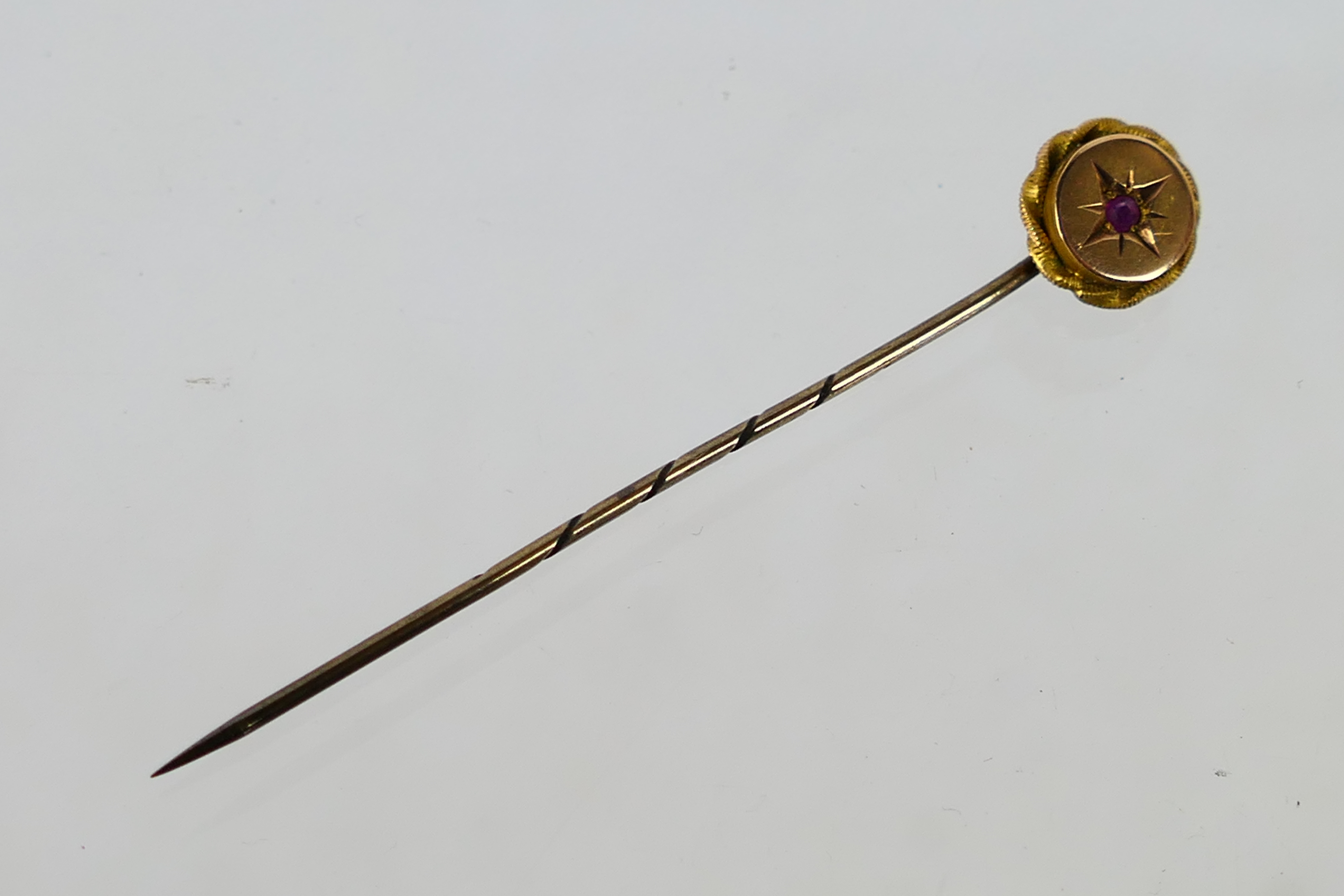 A ruby set stick pin, stamped 9ct, approximately 1.3 grams.