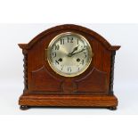 An early 20th century oak cased mantel clock, silvered dial with Arabic numerals,