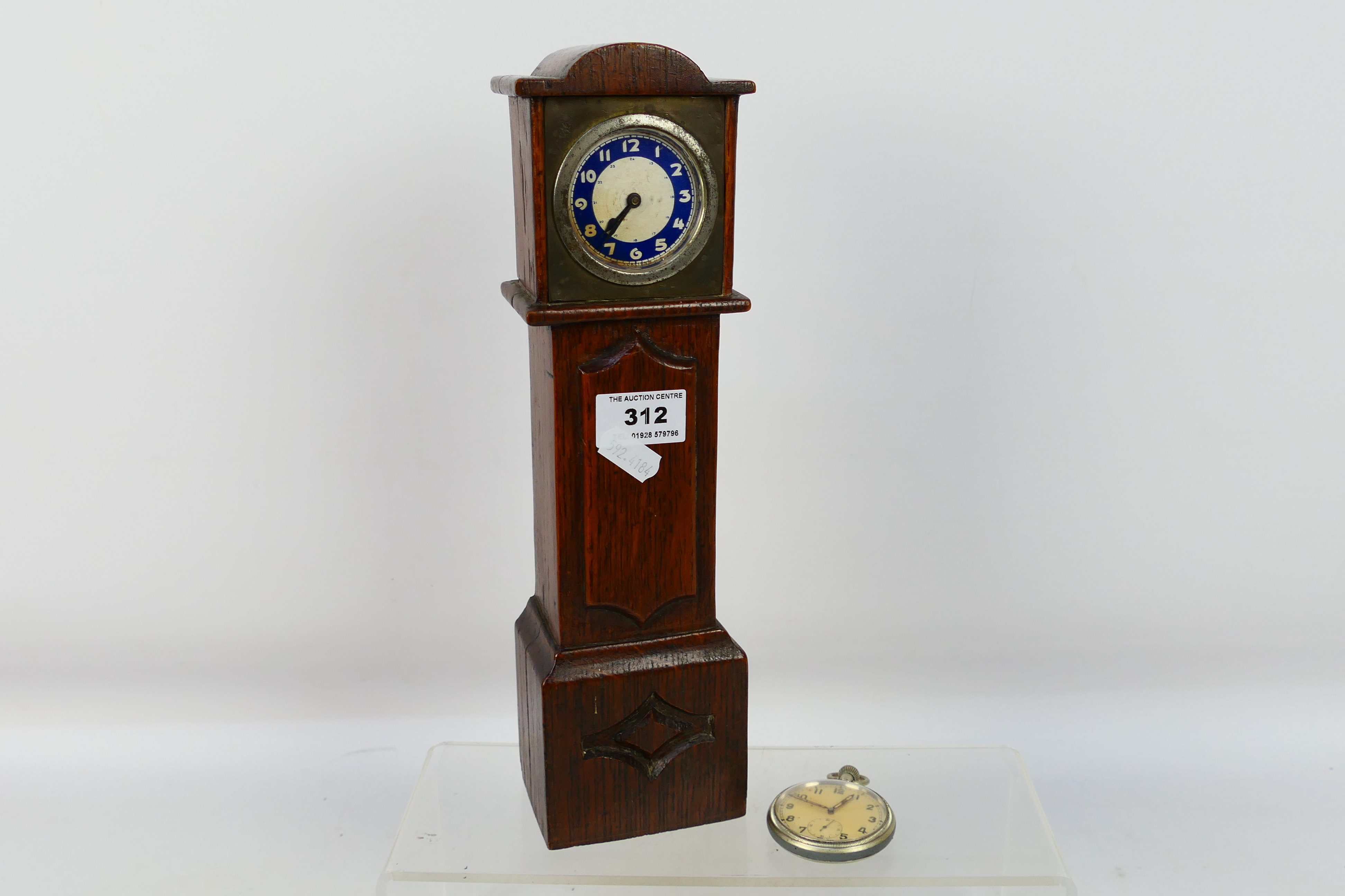 A vintage mantel or desk clock in the form of a longcase clock,