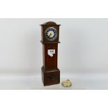 A vintage mantel or desk clock in the form of a longcase clock,