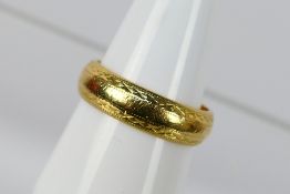 An 18ct yellow gold band ring with chased decoration, size R, approximately 7 grams.