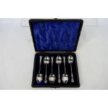 A cased set of six Edwardian coffee spoons with embossed handles and twist stems,